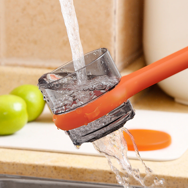 Orange kitchen tool with water flowing through it on a wooden surface.