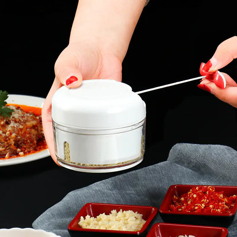 Person using a white handheld grinder with food on a dark surface