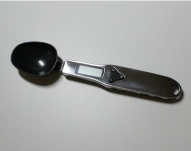 Black electronic measuring spoon on a light gray background