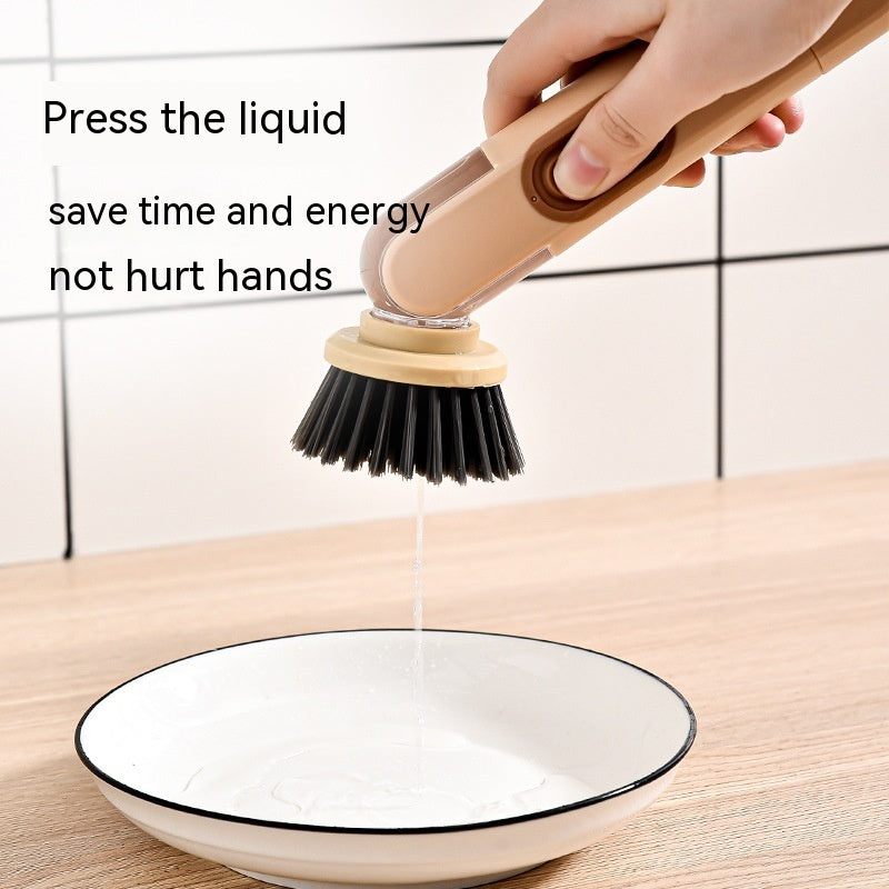 Person using a dishwashing brush with liquid being squeezed onto a plate, set against a tiled wall background.